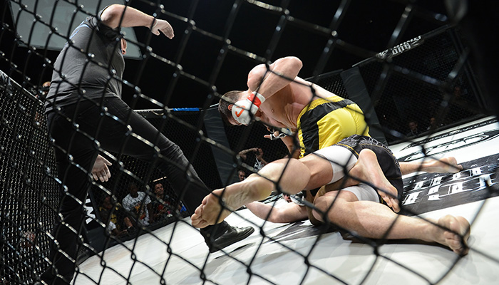 Two-MMA-fighters-and-referee-in-enclosed-metal-cage