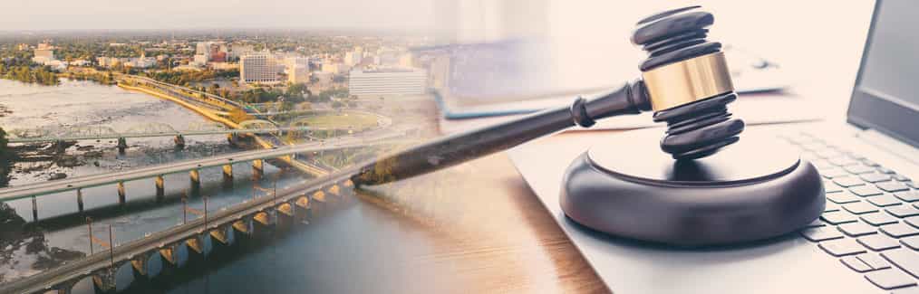 The Trenton skyline behind a judge's gavel, which rests on a laptop computer.