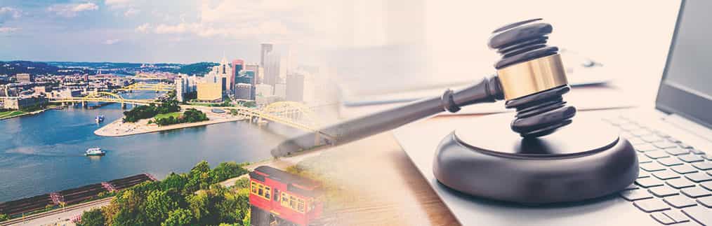 Cityscape of Pittsburgh, Judges gavel and block with laptop placed on a desk.
