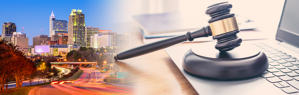 Raleigh skyline behind a judge's gavel, which rests on a laptop computer