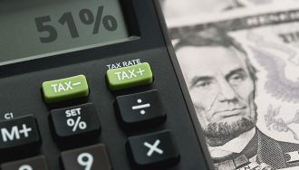 51% on a Tax Calculator Next to a Dollar Bill