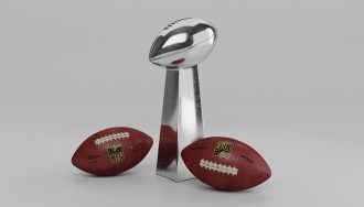 Super Bowl Vince Lombardi Trophy and two American footballs.
