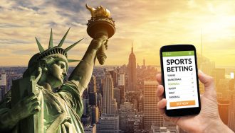 Mobile Phone with Open Sports Betting App next to the Statue of Liberty and NY in the Background