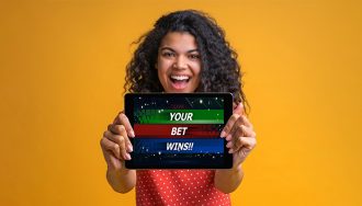 A Happy Femail Player Holding a Tablet with Open Sports Betting App