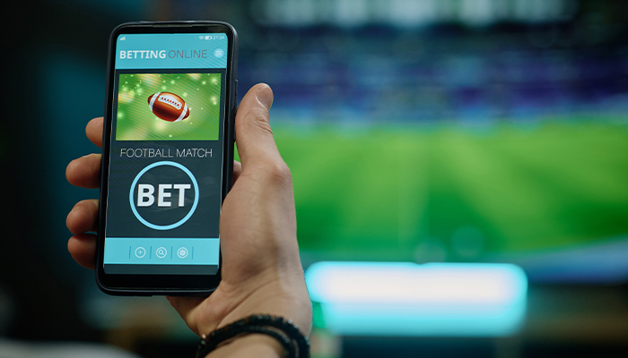 A hand holding a phone while betting on football