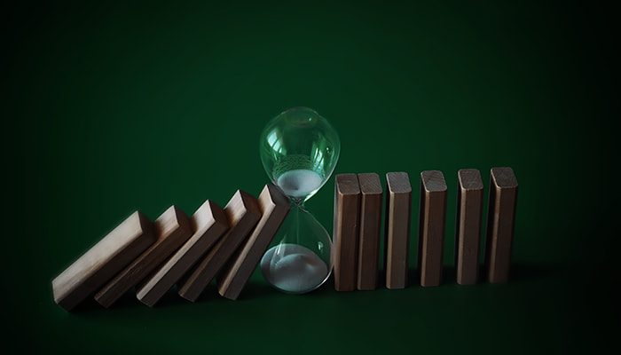 The domino effect stopped midway by an hourglass symbolizing the delay in Missouri’s sports betting launch