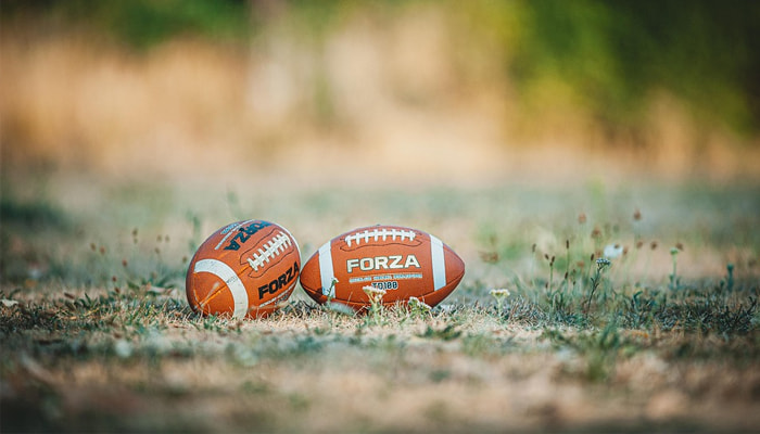 Two footballs on a grassy field